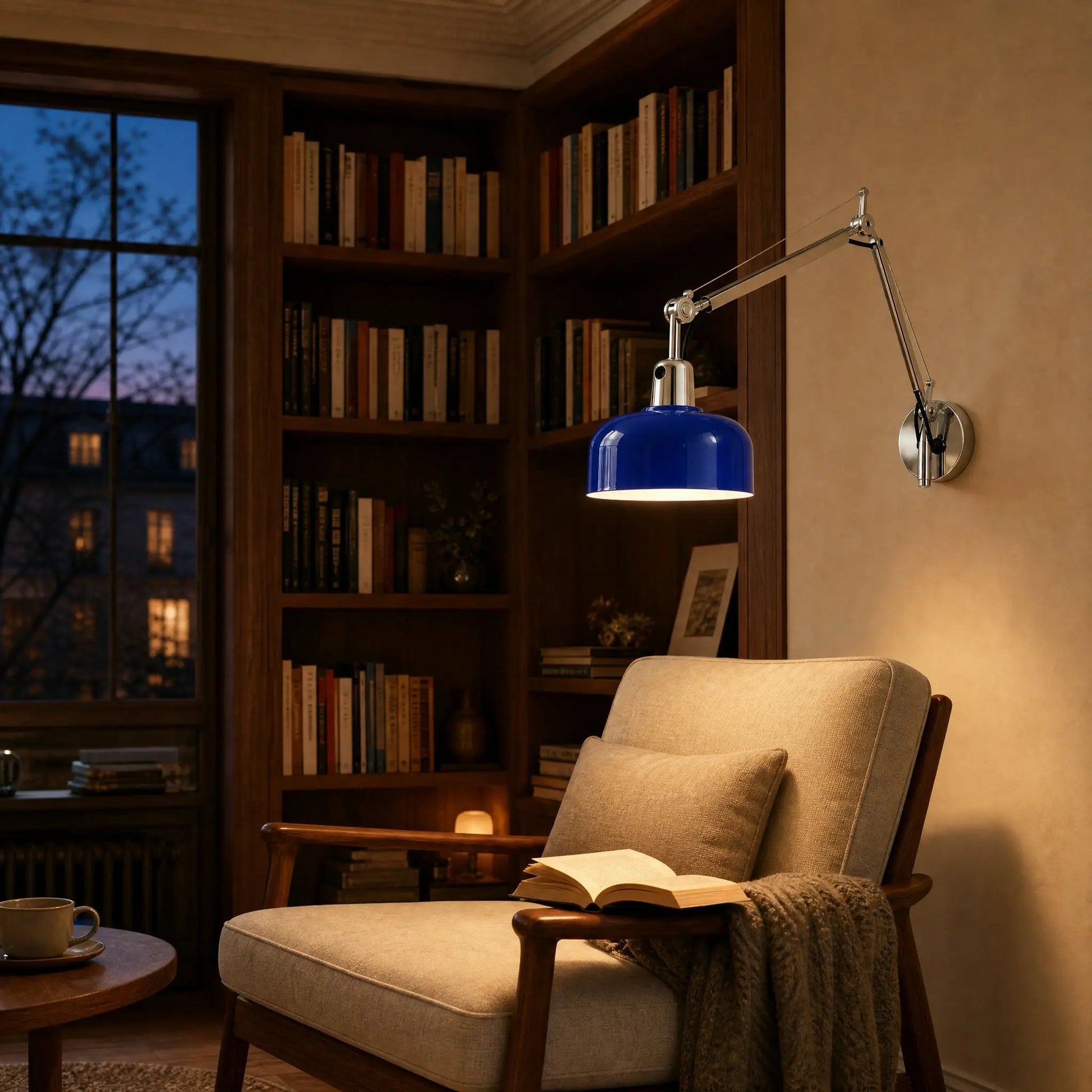 Benra blue swing arm wall light lit above a reading chair, bookshelf at dusk | Wickleigh