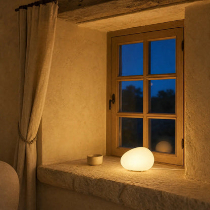 Edlen 22 cm pebble lamp lit on a stone windowsill in the evening | Wickleigh