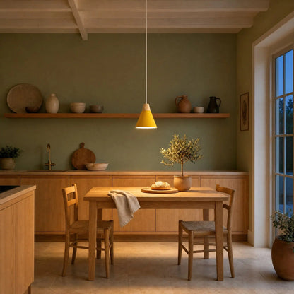 Navlin Scandinavian pendant light, yellow cone switched on above a kitchen table against a sage green wall | Wickleigh