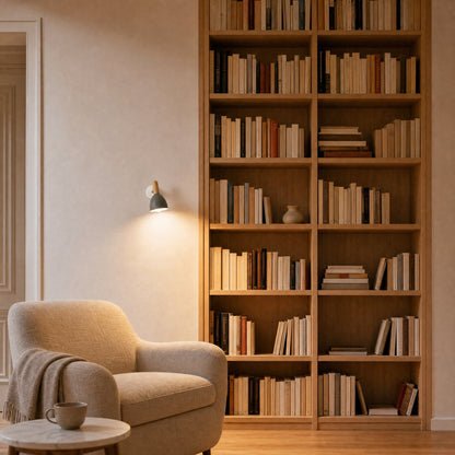 Milna grey Scandinavian wall light lit beside an oak bookcase, evening reading corner | Wickleigh