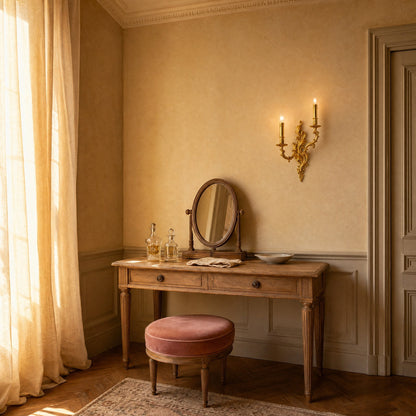 Cerna two-candle gold wall light lit beside a weathered oak dressing table, end of day | Wickleigh