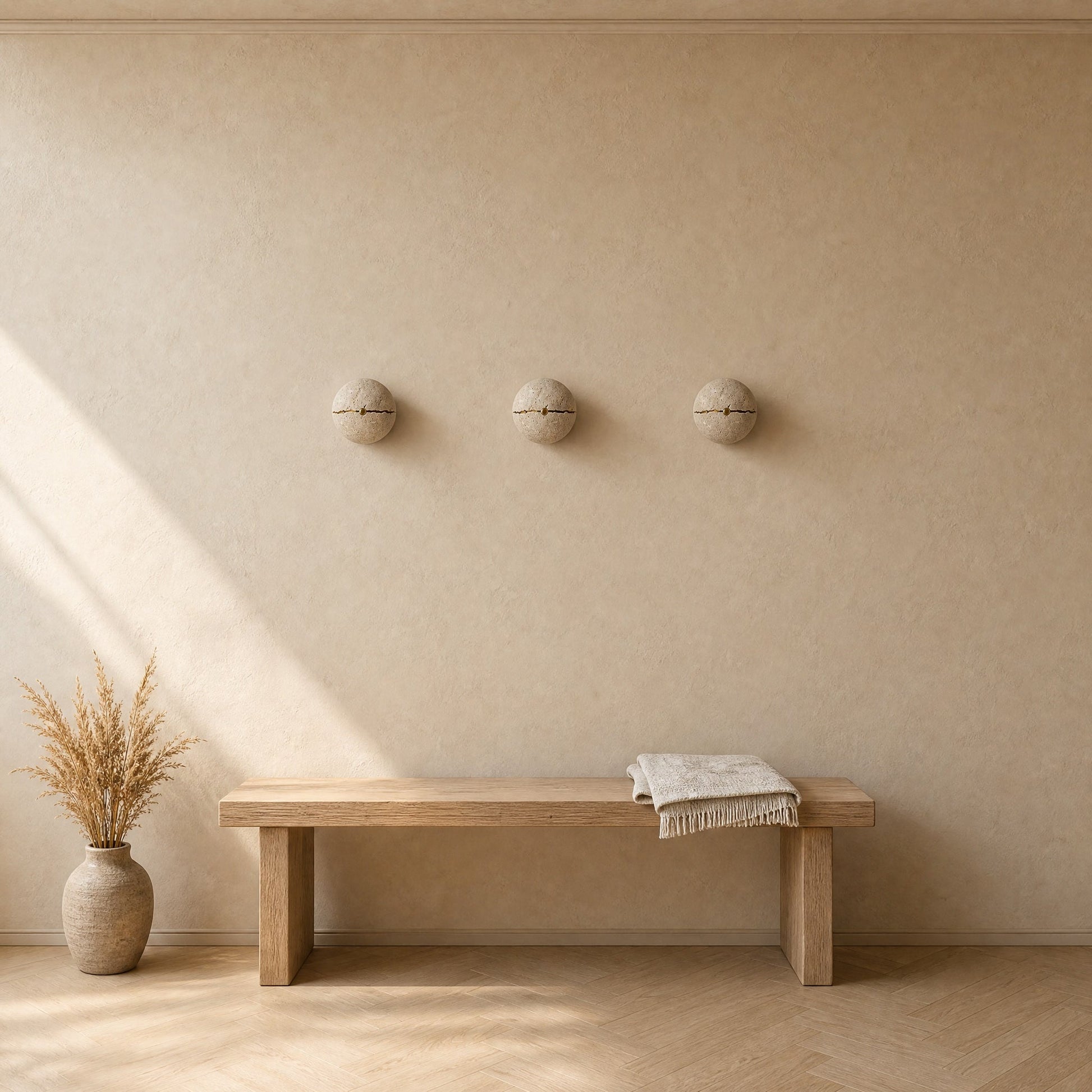 Three Rinen stone wall lights aligned above an oak bench in an entrance, natural light | Wickleigh