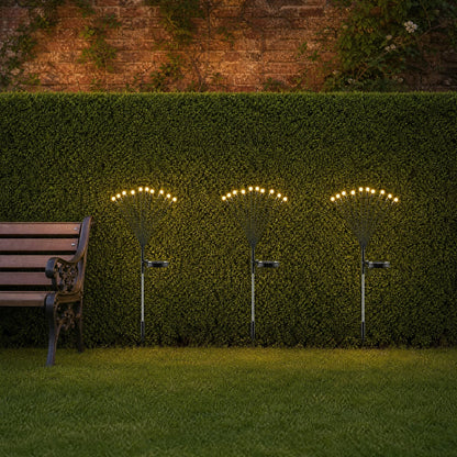 Three Islin solar firefly stakes lined along a lawn edge in front of a trimmed hedge | Wickleigh