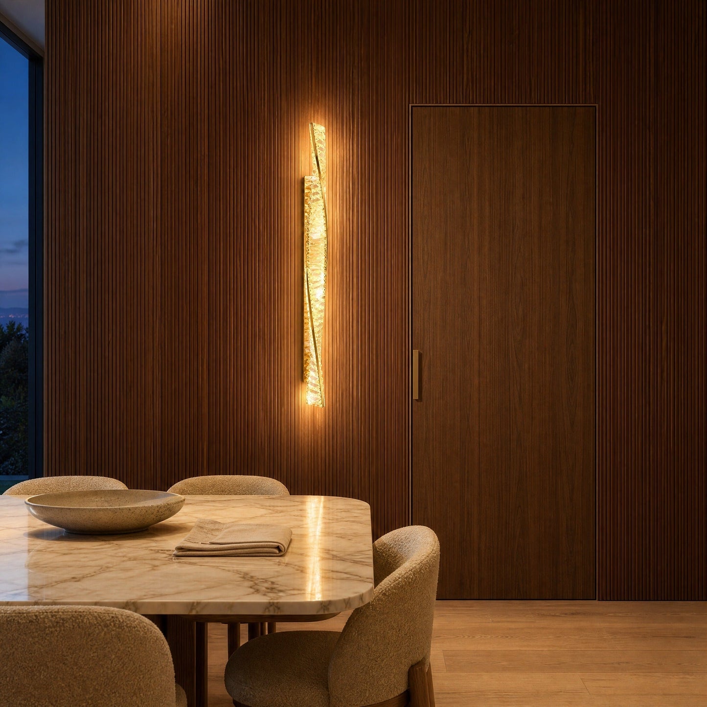 Frena crystal wall light lit against a fluted walnut wall in a villa dining room | Wickleigh
