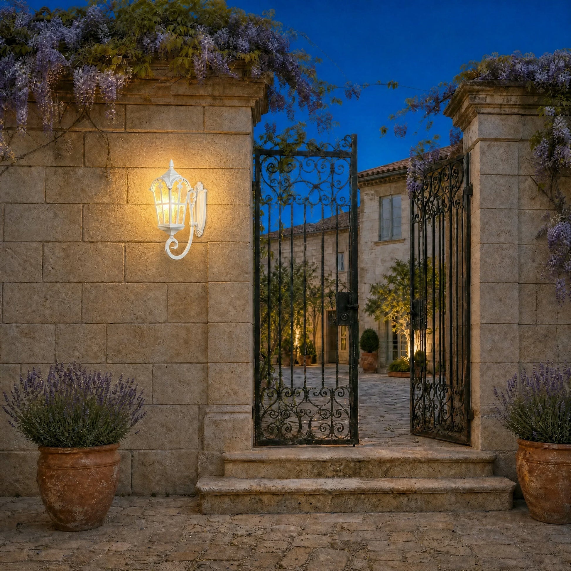 Lovna white outdoor wall lantern lit at nightfall on a stone courtyard pillar | Wickleigh