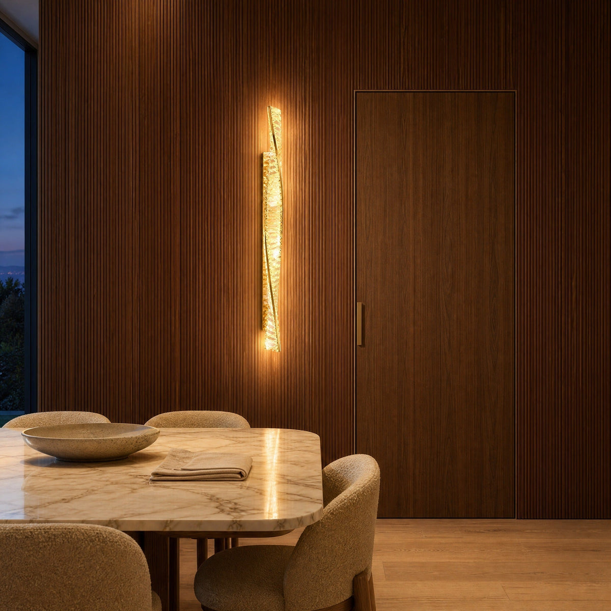 Frena crystal wall light lit against a fluted walnut wall in a villa dining room | Wickleigh