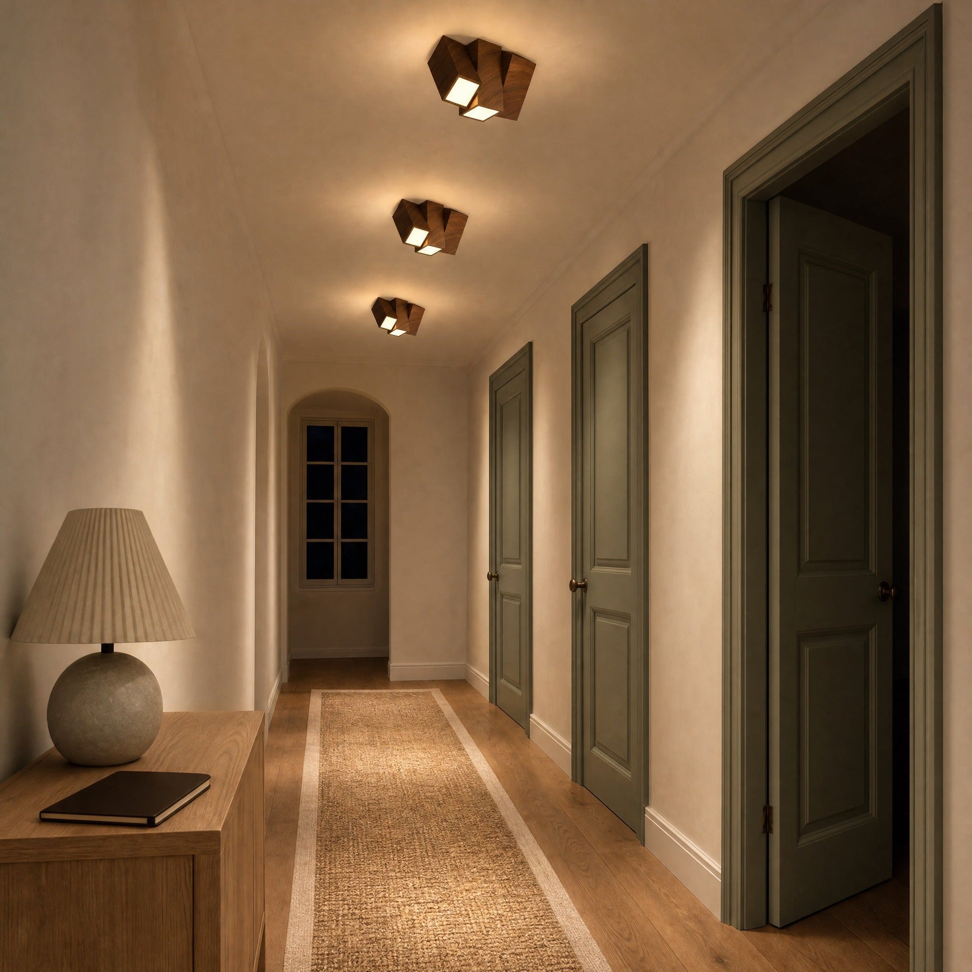Three walnut Gylen ceiling lights aligned along an upstairs hallway ceiling, at night | Wickleigh