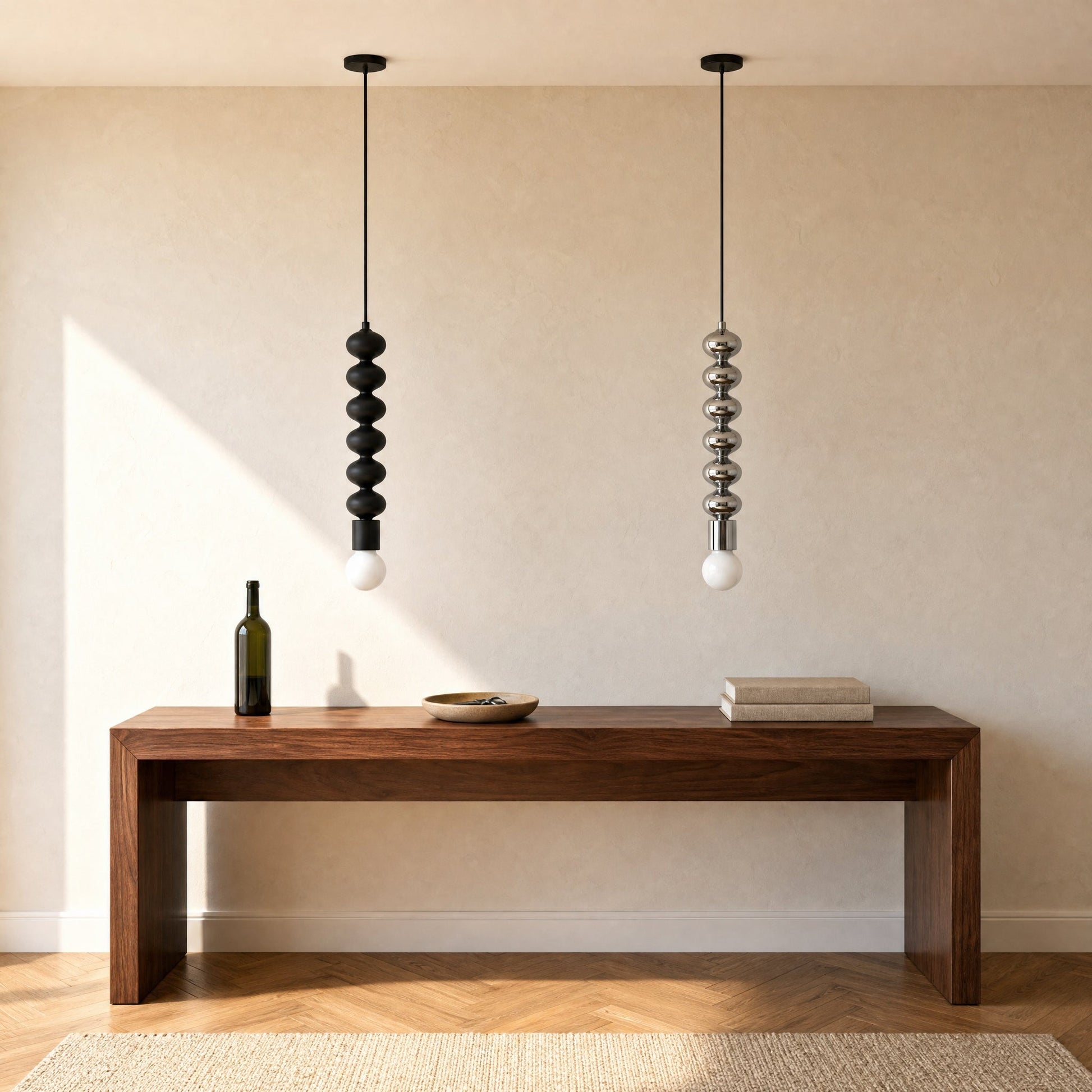 Two Kavlin pendant lights, one matte black and one polished chrome, aligned above a walnut console | Wickleigh