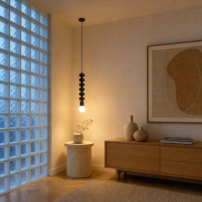 Kavlin pendant light switched on above a travertine side table, in a living room with glass-block partition | Wickleigh